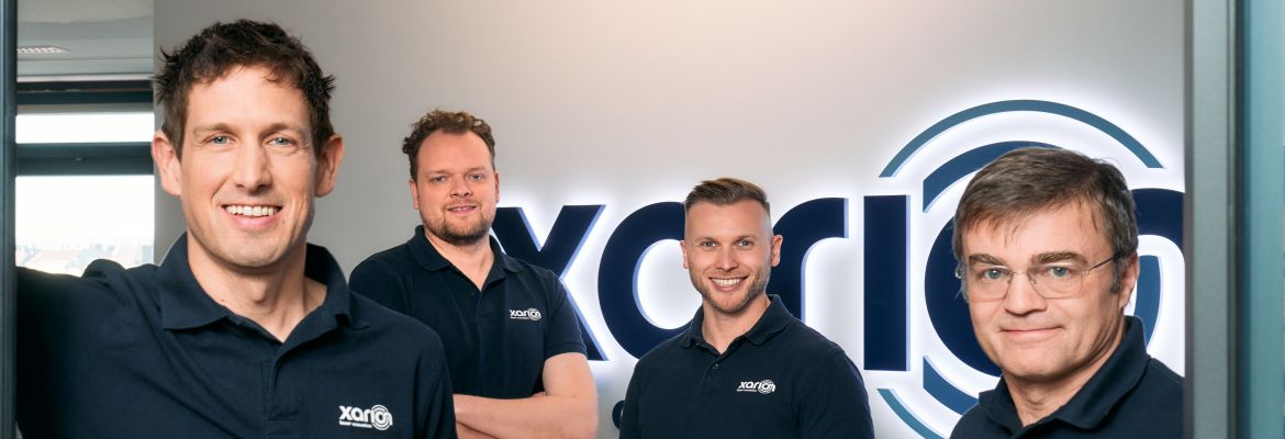 XARION-Gesch&auml;ftsf&uuml;hrung, von links nach rechts: Balthasar Fischer (CEO), Martin Wallner (COO), Josef Poernbacher (CTO) und Georg Zachhuber (CFO), gemeinsam vor dem XARION-Logo